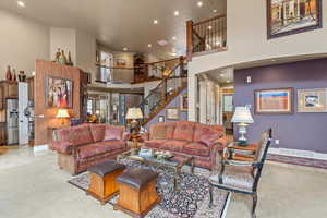 Carpeted living area featuring stairway, a high ceiling, visible vents, and recessed lighting