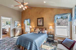 Bedroom with vaulted ceiling, baseboards, connected bathroom, and ceiling fan