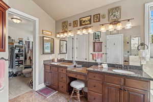 Bathroom with lofted ceiling, a sink, and double vanity