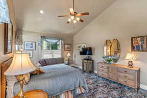 Bedroom with high vaulted ceiling, carpet flooring, baseboards, and ceiling fan