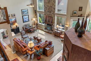 Tiled living room with a high ceiling, a stone fireplace, and plenty of natural light