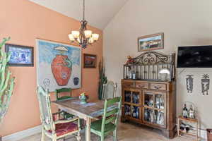 Dining area featuring vaulted ceiling, baseboards, and a notable chandelier