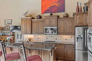 Kitchen featuring a breakfast bar, tasteful backsplash, stainless steel appliances, and dark stone countertops