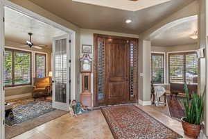 Foyer featuring arched walkways, a ceiling fan, tile patterned flooring, and baseboards