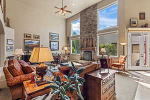 Living area with a fireplace, carpet floors, a high ceiling, and ceiling fan