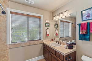 Bathroom featuring toilet, vanity, and visible vents