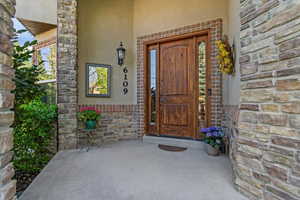 View of exterior entry featuring stucco siding, stone siding, and covered porch