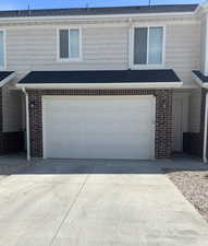 View of front facade with brick siding, an attached garage, and driveway