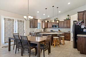 Dining room with vaulted ceiling, recessed lighting, a notable chandelier, and light tile patterned floors