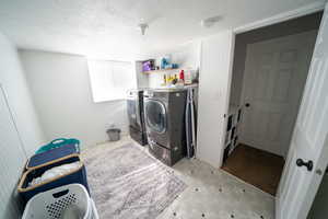 Laundry room with washing machine and clothes dryer, a textured ceiling, light floors, and laundry area
