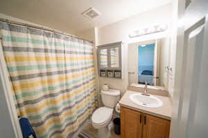 Ensuite bathroom with connected bathroom, vanity, toilet, a shower with shower curtain, and visible vents