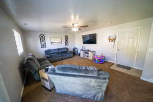 Carpeted living area with baseboards, a ceiling fan, and visible vents