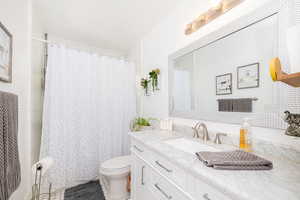 Full bath with tile patterned flooring, toilet, vanity, and a shower with shower curtain