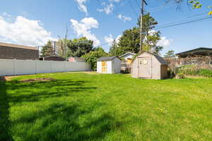 View of yard featuring fence, an outbuilding, and a storage shed