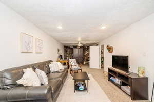 Living area with recessed lighting, a ceiling fan, carpet floors, and a textured ceiling