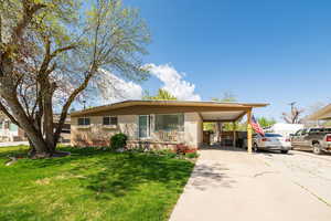 View of front of property with concrete driveway, a front lawn, brick siding, and an attached carport