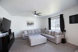 Carpeted living area with a ceiling fan.