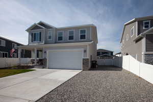 View of front of home with driveway, a porch, stone siding, fence, and a large RV Pad.