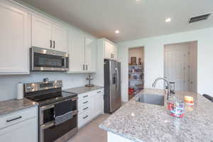 Kitchen featuring white cabinets, stainless steel appliances, and light wood-style flooring