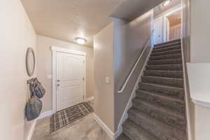 Entrance foyer with stairs, baseboards, and a textured ceiling