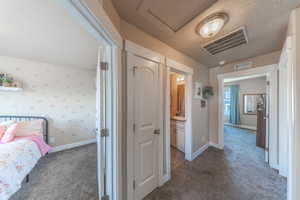 Hallway featuring carpet flooring, visible vents, and baseboards