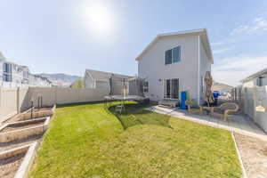Back of house with a vegetable garden, a yard, entry steps, a patio area, and a trampoline
