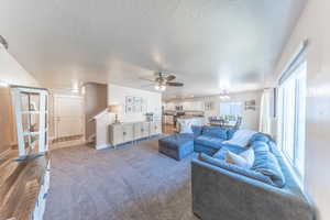 Living area with baseboards, carpet, a textured ceiling, and a ceiling fan