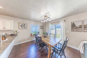 Dining space with baseboards, a textured ceiling, and dark wood finished floors