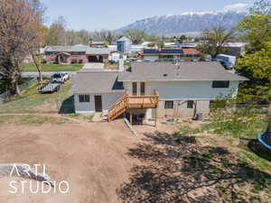 Back of house featuring a deck with mountain view, a shingled roof, a fenced backyard, a residential view, and stairs