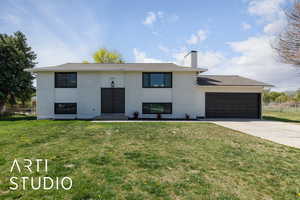 Split foyer home featuring concrete driveway, an attached garage, fence, a front yard, and brick siding