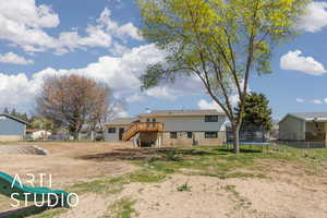 Back of house with a wooden deck, a trampoline, stairway, and fence