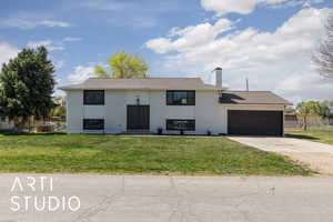 Split foyer home with a garage, driveway, fence, a front yard, and brick siding