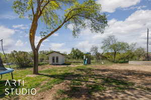 View of yard with a playground, fence, an outdoor structure, french doors, and a trampoline