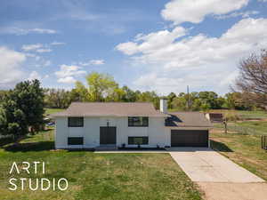 Split foyer home featuring a chimney, a front lawn, driveway, fence, and a garage