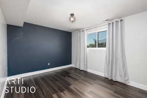Empty room featuring baseboards, visible vents, and dark wood-type flooring