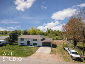 Bi-level home featuring roof with shingles, a chimney, concrete driveway, a garage, and a front yard
