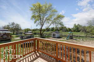 Deck with a playground, a shed, an outdoor structure, a lawn, and a trampoline