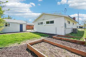 Rear view of property with a chimney, fence, a yard, and a vegetable garden