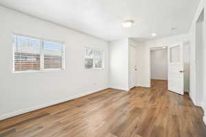 Unfurnished bedroom featuring baseboards, wood finished floors, and a textured ceiling