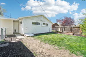 Back of house with fence, a lawn, a garden, and brick siding