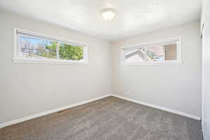Carpeted empty room with visible vents, baseboards, and a healthy amount of sunlight