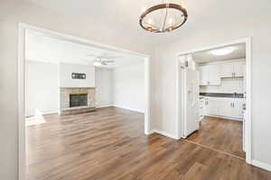 Unfurnished living room featuring dark wood-type flooring, baseboards, a sink, and ceiling fan with notable chandelier