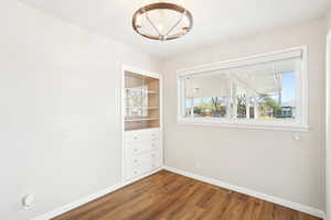 Empty room with baseboards, wood finished floors, visible vents, and a chandelier