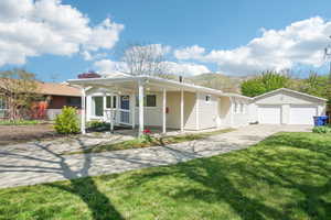 View of front of home featuring a detached garage, a front lawn, driveway, an outdoor structure, and a porch