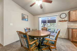Dining space with dark carpet, ceiling fan, lofted ceiling, and visible vents
