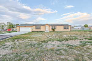 Ranch-style house featuring concrete driveway, an attached garage, and fence