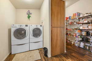 Laundry room with baseboards, wood finished floors, washer and dryer, and laundry area