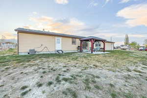 Rear view of property featuring central AC unit, a gazebo, a yard, and a patio
