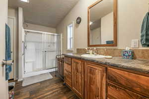 Full bathroom featuring wood finished floors, vanity, and a stall shower