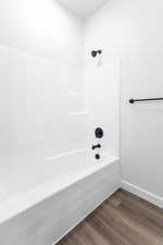 Bathroom featuring shower / bathing tub combination, wood finished floors, and baseboards